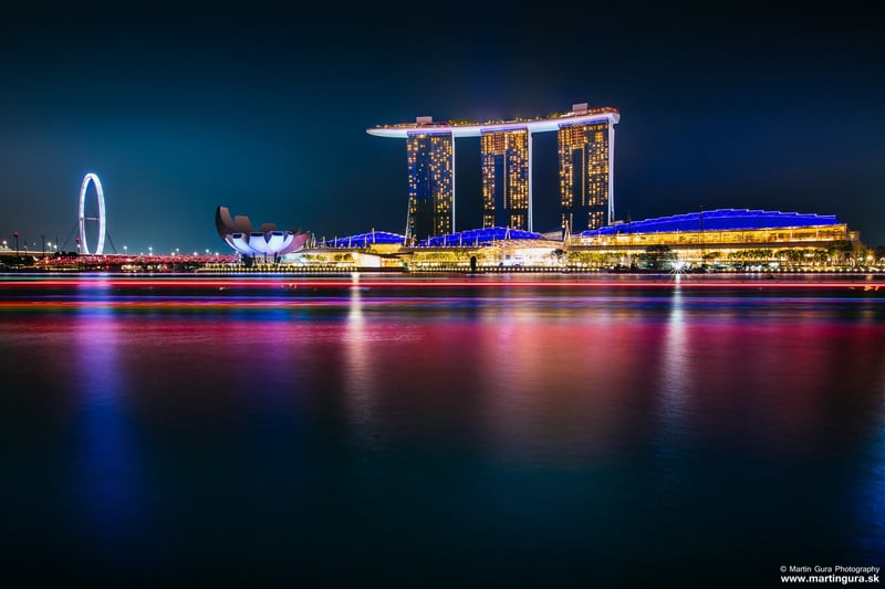 Hotel Marina Bay Sands a Singapore Flyer nasvietené v noci nad zátokou.