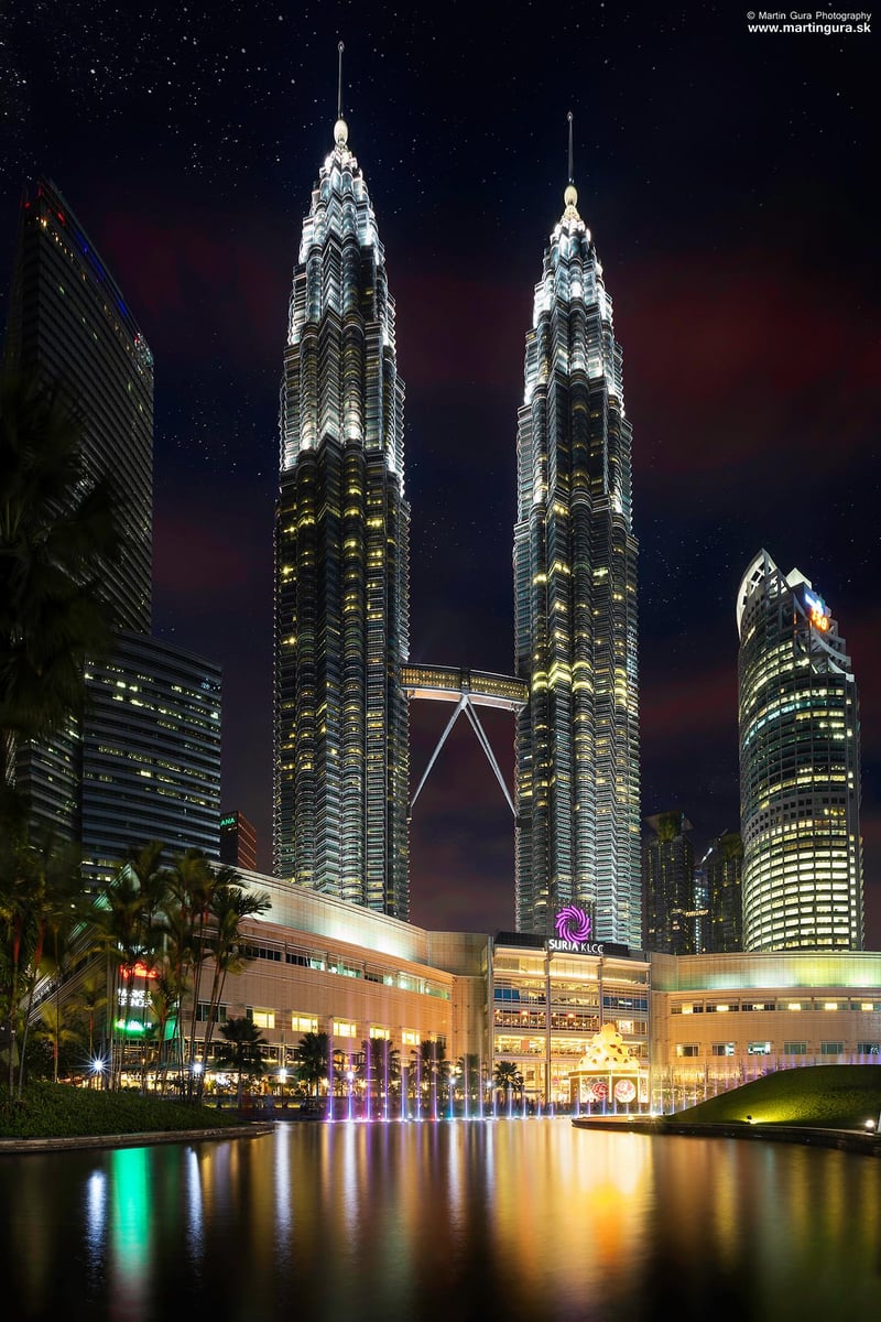Veže Petronas Twin Towers v Kuala Lumpur osvetlené v noci s odrazom v jazere.