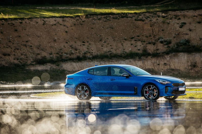Modrá Kia Stinger v drifte na škole šmyku počas eventovej fotodokumentácie.