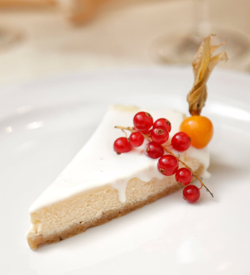 Reklamná fotografia cheesecaku zdobeného červenými ríbezľami.