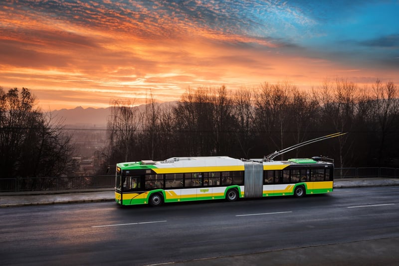 Žltozelený trolejbus Solaris MHD Žilina pri západe slnka s panorámou hôr v pozadí.