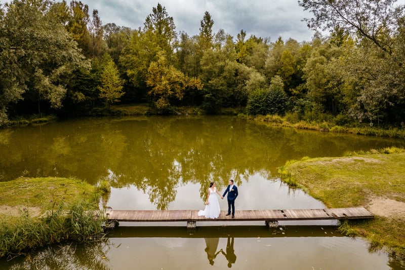 Novomanželia na móle nad jazerom v jeseni z drona