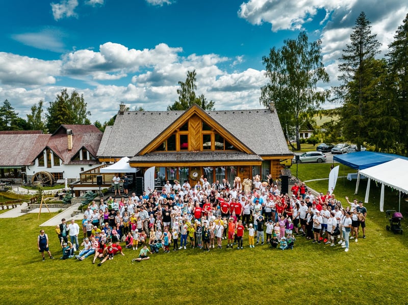 Veľká skupinová svadobná fotografia pred drevenicou z drona