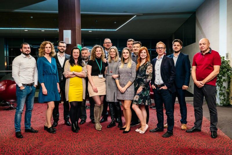 Skupinová fotka organizačného tímu eventu v elegantnom outfite v hotelovom átriu