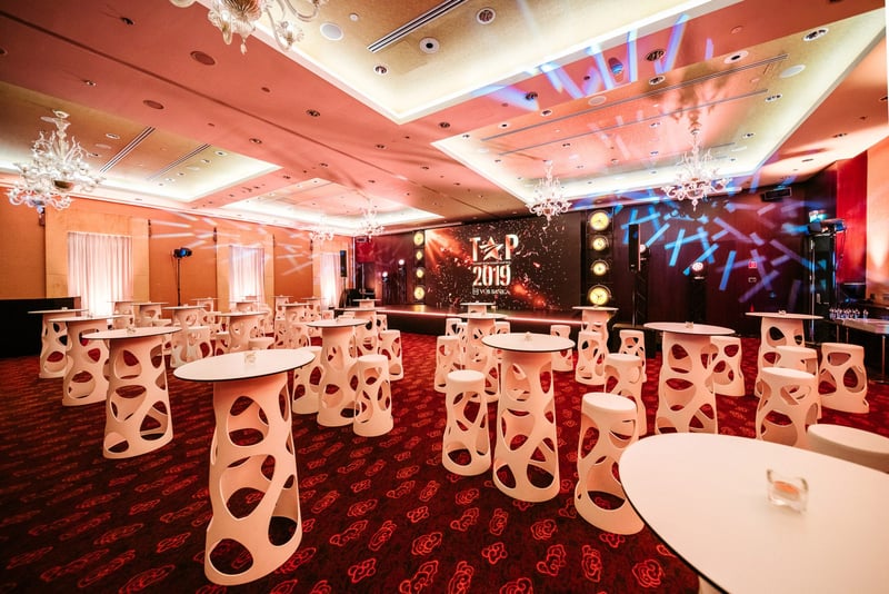 Reprezentačná sála s bielymi cocktail stolmi pripravená na gala večer s odovzdávaním cien