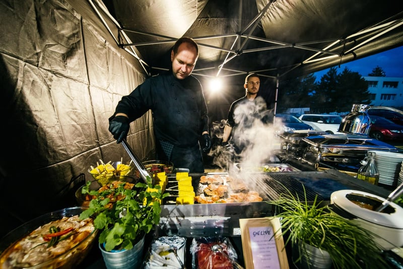 Kuchár pripravuje pokrmy v outdoor catering stojane s parou a varičmi