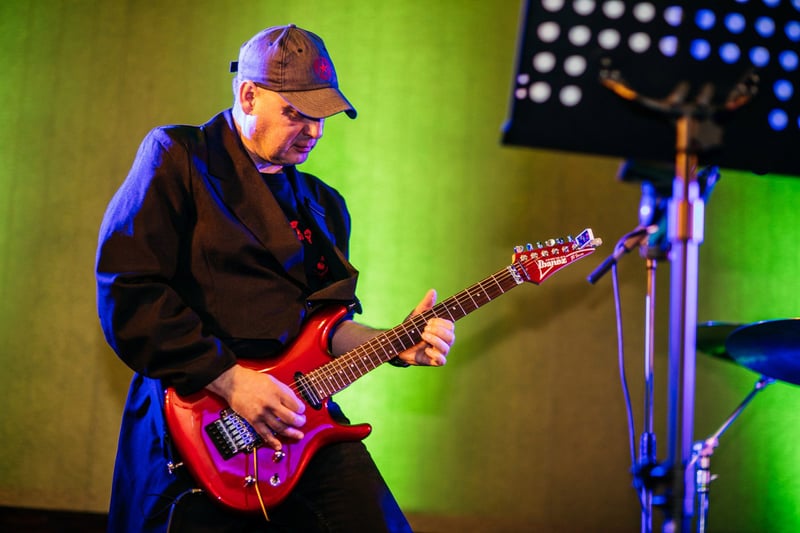 Gitarista s červenou elektrickou gitarou hrá na pódiu počas koncertu