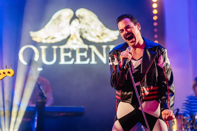 Spevák v charakteristickom kostýme s mikrofónom napodobňuje Freddieho Mercuryho počas Queen tribute show