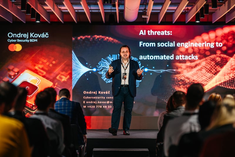 Speaker pred LED panelom s témou AI hrozieb a sociálneho inžinierstva počas tech keynote prednášky