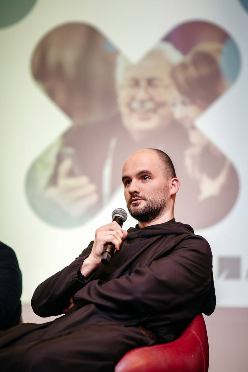 Hosť panelovej diskusie s mikrofónom v sediacej polohe počas konferencie