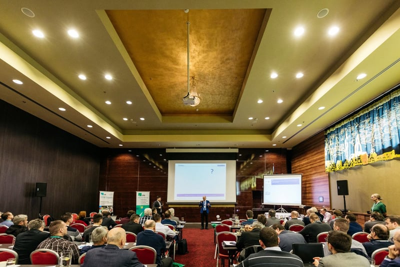 Pohľad na pódium s dvoma prednášajúcimi pred radmi účastníkov v konferenčnej sále