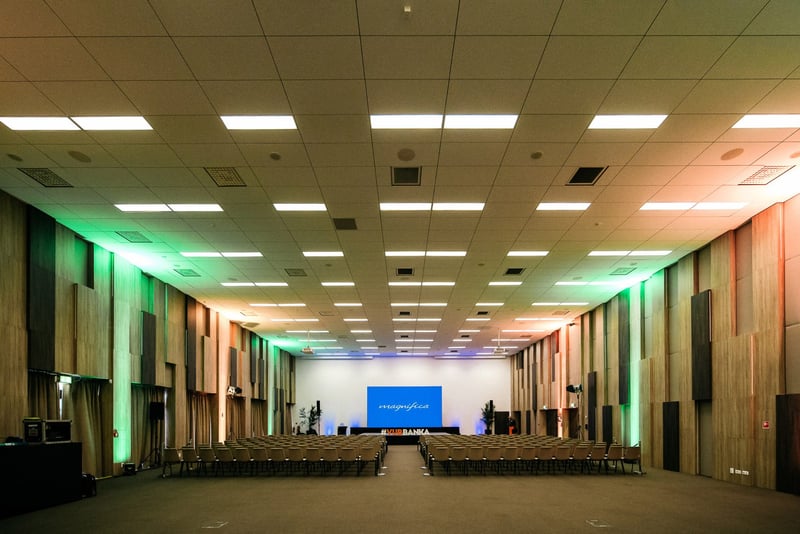 Veľká prázdna konferenčná sála s farebným uplighting osvetlením a pódiom pripravená pred eventom