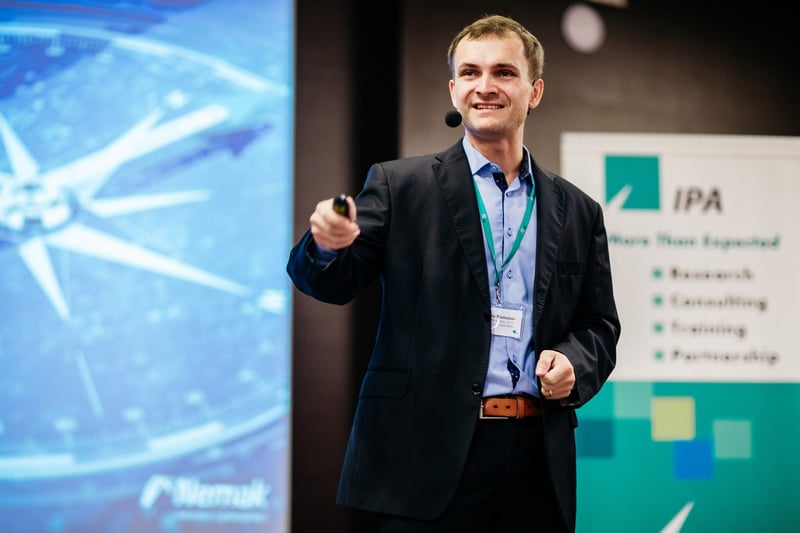 Prednášajúci s prezentérom v ruke ukazuje na slide počas konferencie