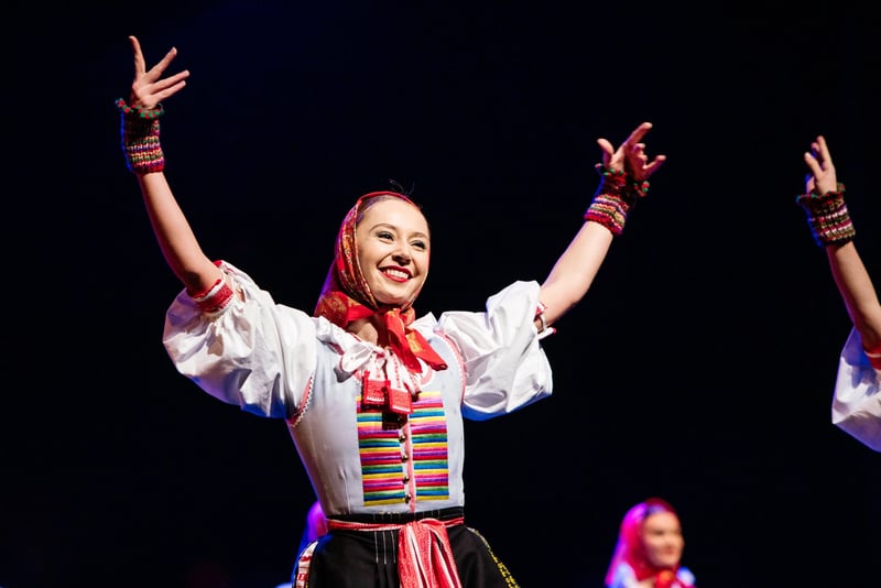 Folklórna speváčka v slovenskom kroji s vyšívanou blúzou s rozpaženými rukami počas vystúpenia