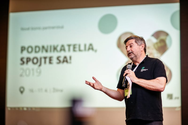 Rečník s mikrofónom na podnikateľskej konferencii v Žiline pred prezentáciou