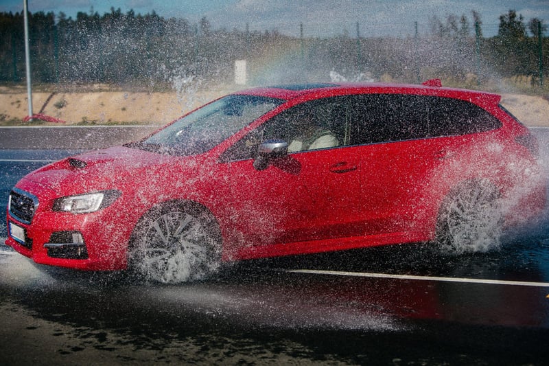 Červené športové auto v ostrej zákrute na vodnom teste školy šmyku, sprej vody okolo kolies