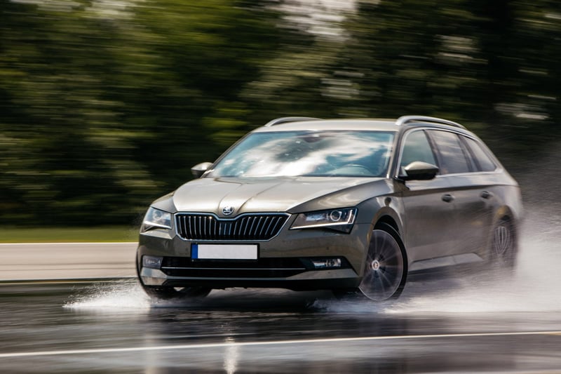 Kombi auto v rýchlej jazde po mokrom asfalte počas školy šmyku, motion blur kolies