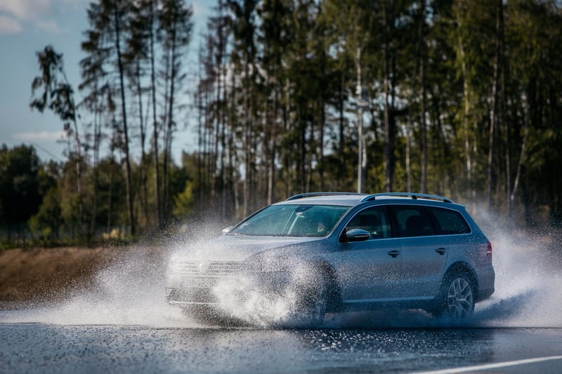 Strieborné kombi auto pri prejazde mokrým úsekom okruhu počas školy šmyku