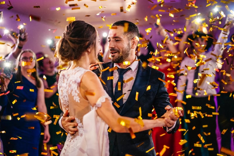 Svadobná fotografia novomanželov pri tanci so zlatými konfetami